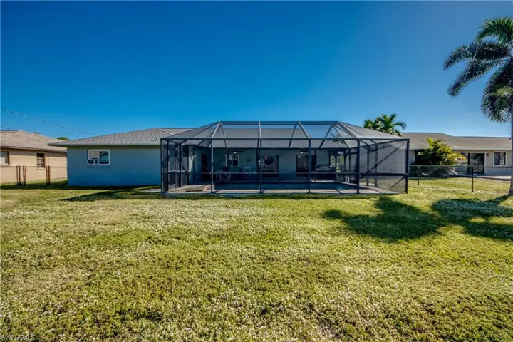 Back of property with glass enclosure and a yard