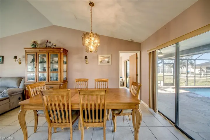 Dining area featuring an inviting chandelier, light tile patterned floors, and vaulted ceiling