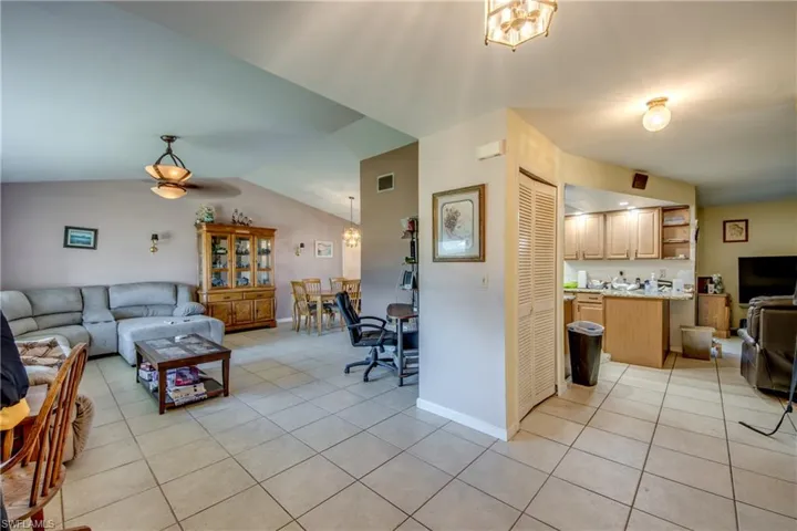 Living room featuring light tile patterned floors, ceiling fan, and lofted ceiling