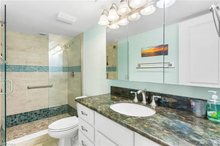 Guest bathroom with custom tile, new vanity/plumbing/lighting fixtures. Heavy glass shower doors.