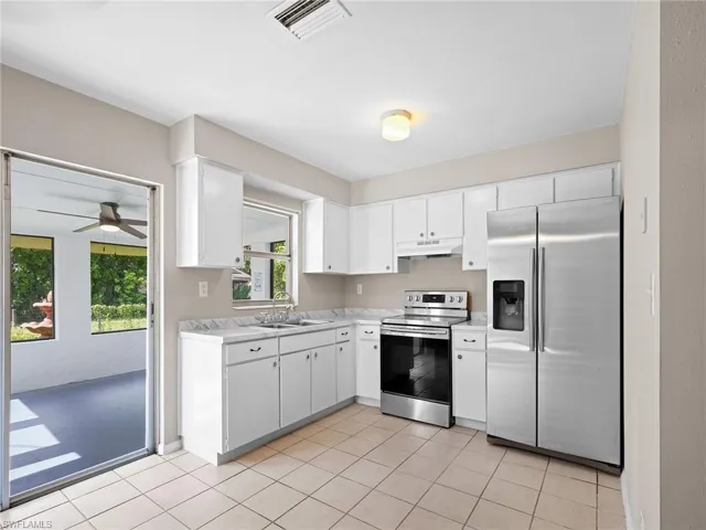 Kitchen featuring stainless steel appliances, light countertops, a ceiling fan, white cabinetry, and light tile patterned flooring