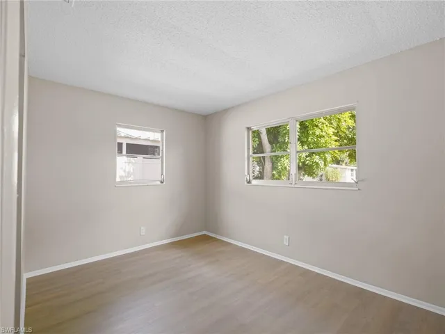 Empty room featuring a textured ceiling, plenty of natural light, and wood finished floors