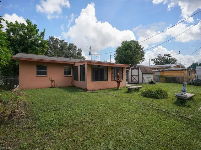 Rear view of house featuring stucco siding and a storage shed