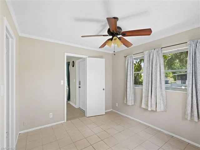 Unfurnished bedroom with crown molding, light tile patterned floors, and ceiling fan