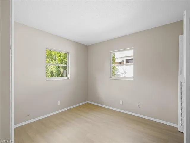 Unfurnished bedroom with light wood-style floors, multiple windows, and a textured ceiling