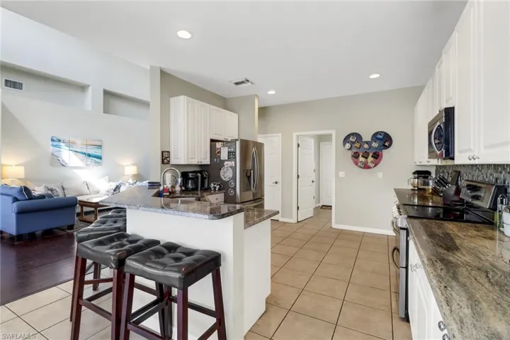 Kitchen featuring a kitchen breakfast bar, kitchen peninsula, stainless steel appliances, sink, and white cabinets