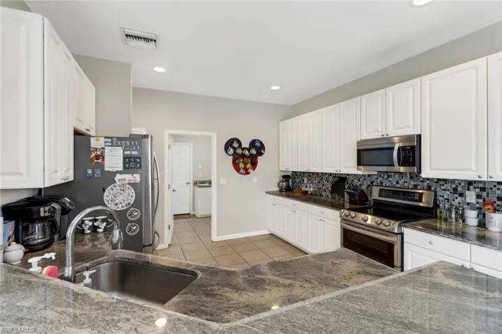 Kitchen featuring white cabinetry, tasteful backsplash, appliances with stainless steel finishes, and sink