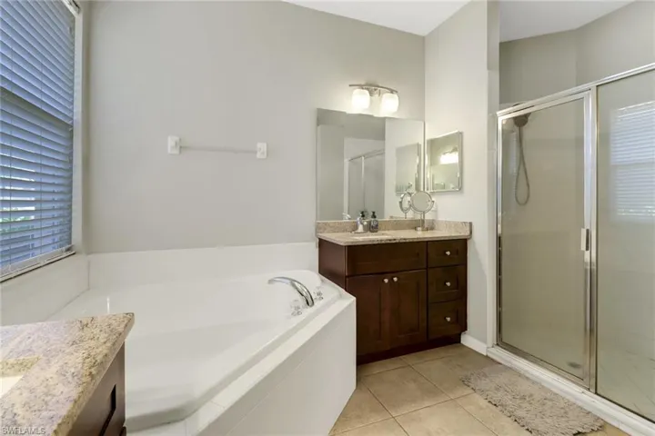 Bathroom with vanity, tile patterned floors, and plus walk in shower