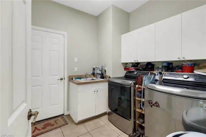 Clothes washing area featuring sink, independent washer and dryer, cabinets, and light tile patterned floors