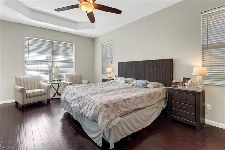 Bedroom featuring a raised ceiling, dark hardwood / wood-style floors, and ceiling fan