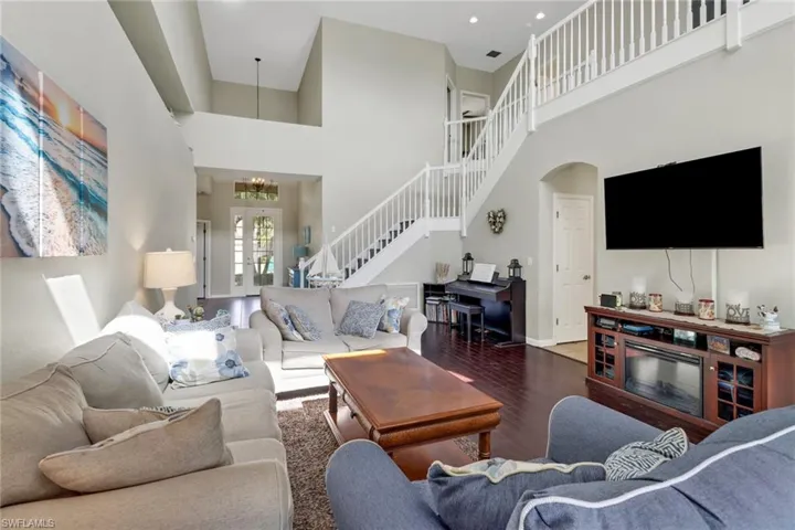 Living room featuring wood-type flooring, a high ceiling, and a chandelier