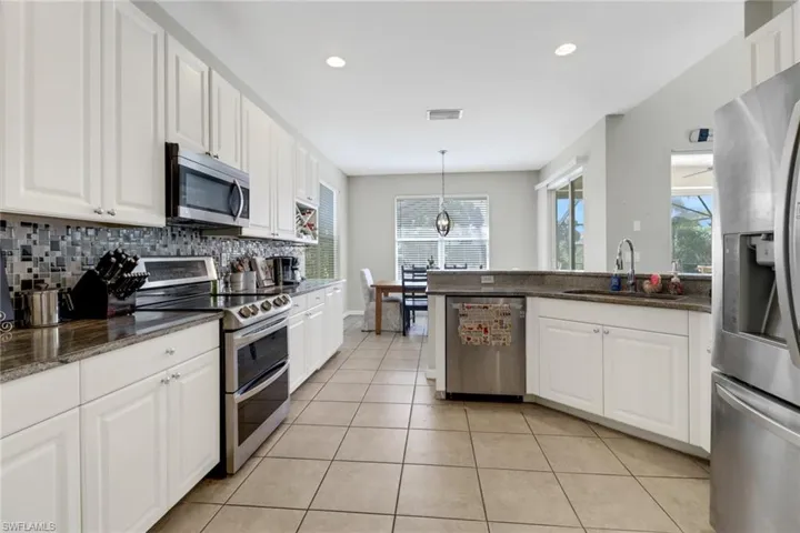 Kitchen featuring white cabinetry, appliances with stainless steel finishes, sink, and pendant lighting