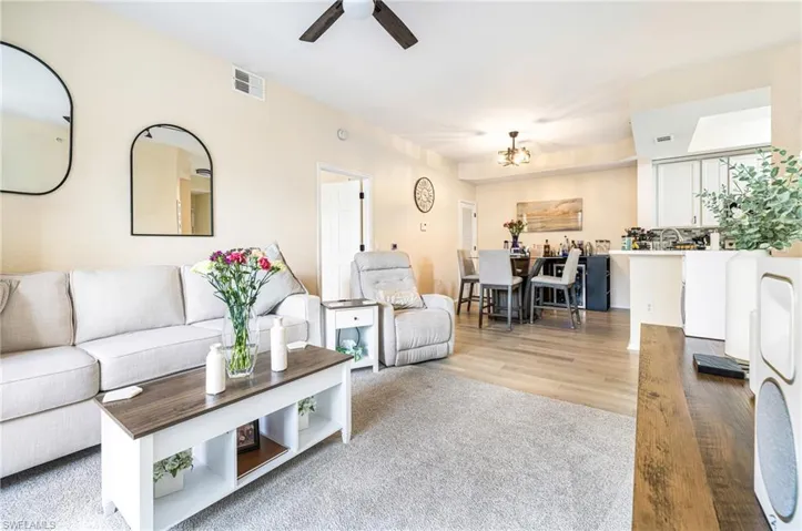 Living area with a ceiling fan, a chandelier, and light wood-style flooring