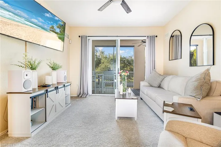 Living area featuring ceiling fan, light carpet, and healthy amount of natural light