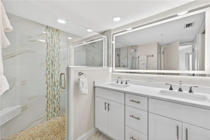 Primary Bathroom with double vanity, a marble finish shower, and recessed lighting