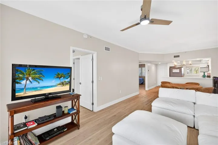 Living area with light wood-type flooring, a ceiling fan, ornamental molding, and hanging lights