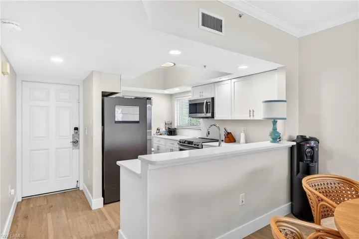 Kitchen featuring stainless steel appliances, a peninsula, white cabinets, light wood-style flooring, and recessed lighting