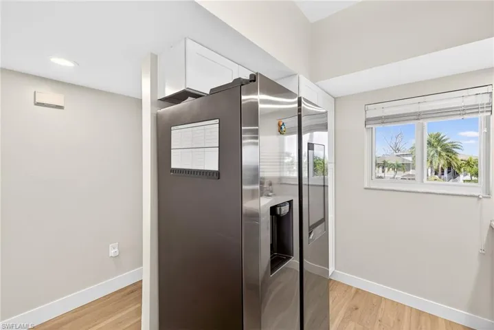 Kitchen featuring stainless steel fridge with ice dispenser, light wood-style floors, and white cabinets