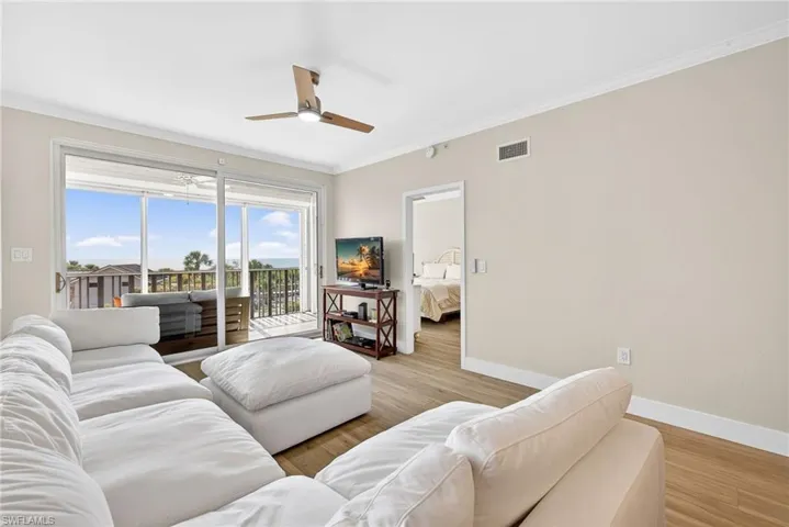 Living area with crown molding, light wood-style floors, and a ceiling fan