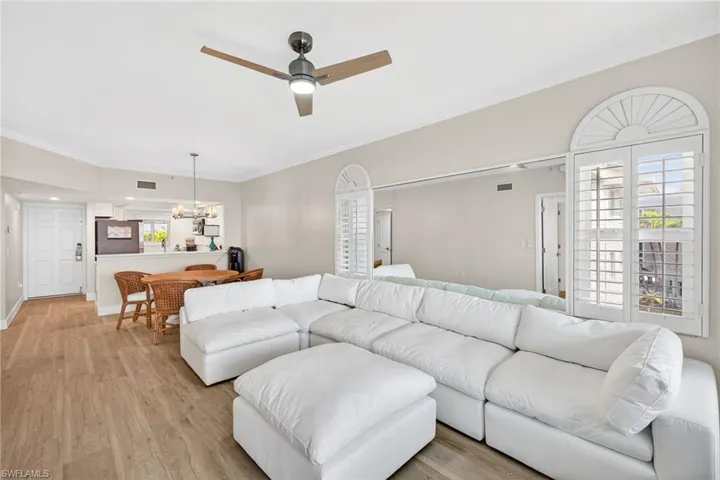 Living area with light wood-type flooring, ornamental molding, a ceiling fan, and hanging lights
