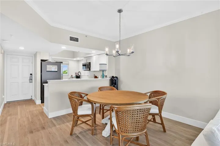 Dining area featuring crown molding, light wood-type flooring, and hanging lights