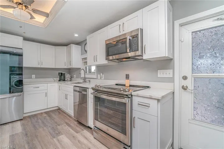 SHAKER STYLE CABINETRY.  QUARTZ COUNTERTOPS.  STAINLESS STEEL APPLIANCES.  STAINLESS STEEL UNDER-MOUNT SINK W/HIGH ARC FAUCET.  RECESSED LIGHTING.  LIGHTED TRAY CEILING.  WOOD-LOOK VINYL PLANK FLOORING. LAUNDRY AREA IS LOCATED TO RIGHT.