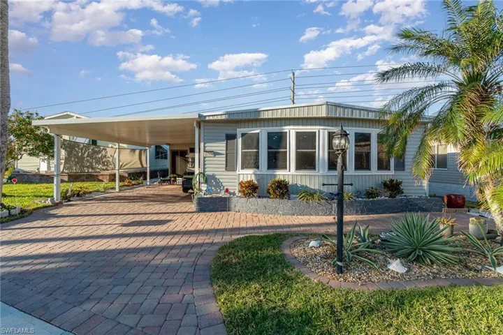 FRONT OF HOME.  DECORATIVE SHUTTERS.  PAVERD DRIVE.  COVERED PARKING.