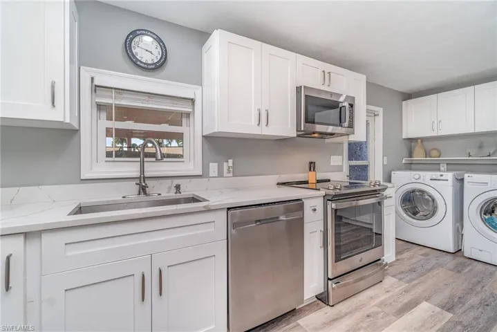 SHAKER STYLE CABINETRY.  QUARTZ COUNTERTOPS.  STAINLESS STEEL APPLIANCES.  STAINLESS STEEL UNDER-MOUNT SINK W/HIGH ARC FAUCET.  RECESSED LIGHTING.  LIGHTED TRAY CEILING.  WOOD-LOOK VINYL PLANK FLOORING. LAUNDRY AREA IS LOCATED TO RIGHT.