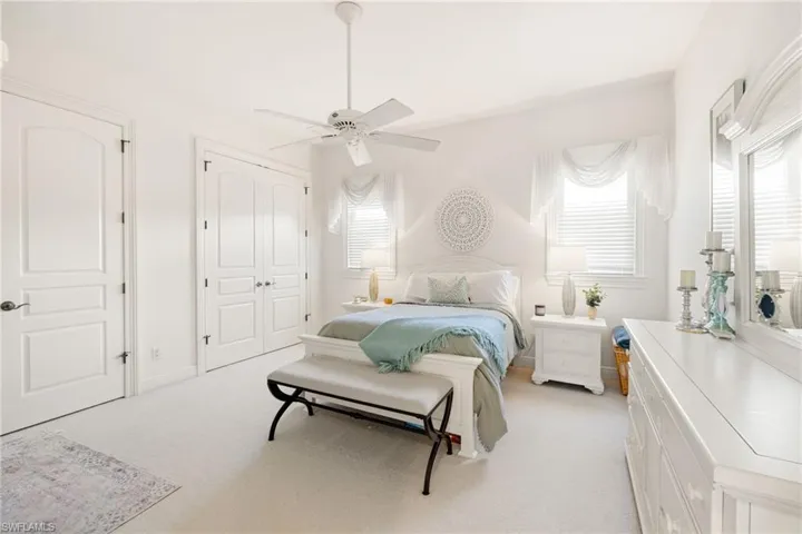Bedroom with light carpet, a closet, and a ceiling fan