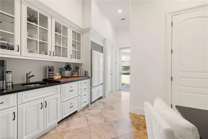 Bar featuring crown molding, white cabinets, glass insert cabinets, paneled built in fridge, and recessed lighting