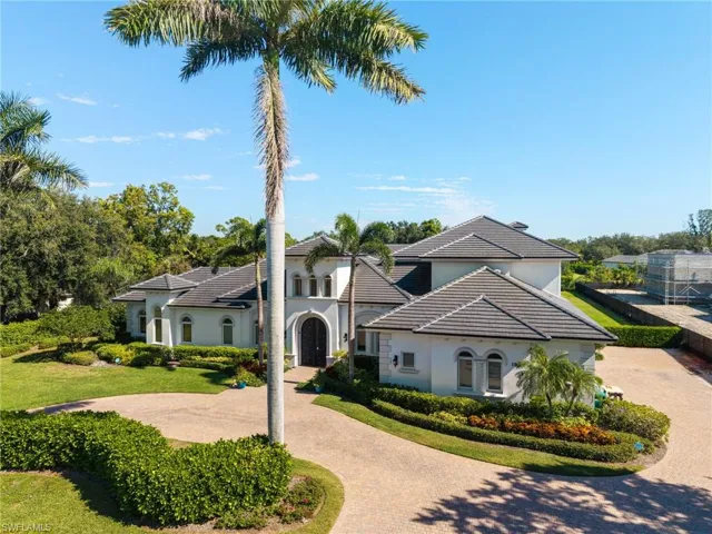 View of front facade featuring stucco siding, curved driveway, a tile roof, and a front lawn