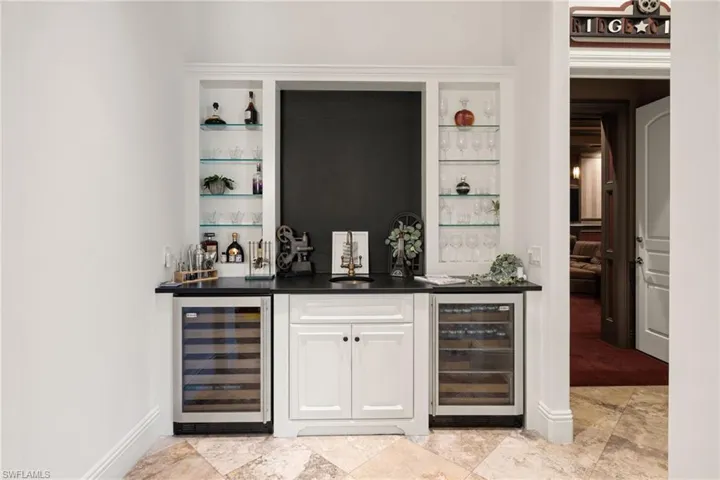 Indoor wet bar with wine cooler and white cabinetry