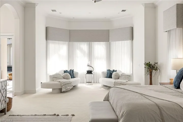 Carpeted bedroom featuring arched walkways and crown molding