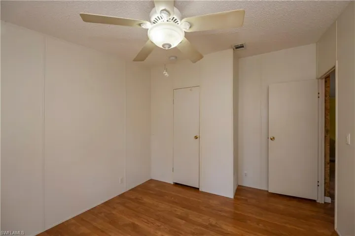 Unfurnished bedroom with a textured ceiling, hardwood / wood-style floors, and ceiling fan