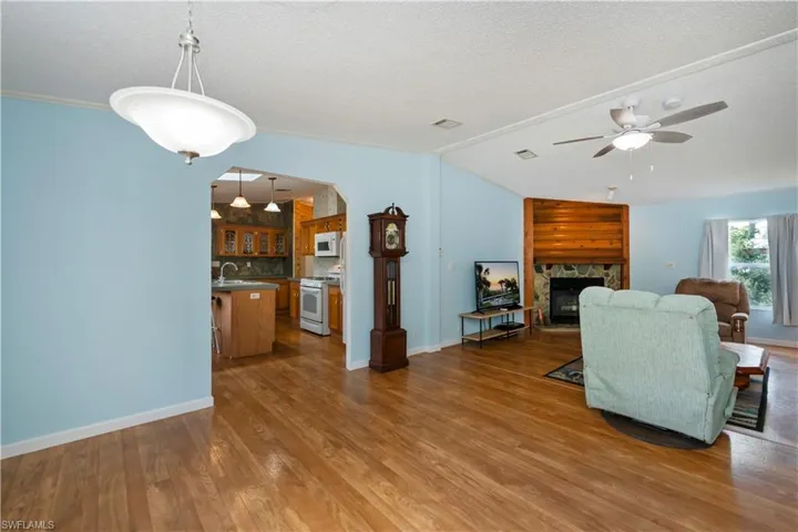 Living room with a fireplace, a textured ceiling, ceiling fan, ornamental molding, and hardwood / wood-style floors