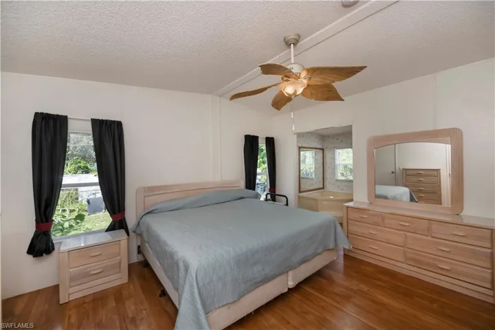 Bedroom with a textured ceiling, wood-type flooring, and ceiling fan