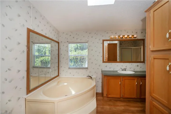 Bathroom with a textured ceiling, wood-type flooring, vanity, and shower with separate bathtub