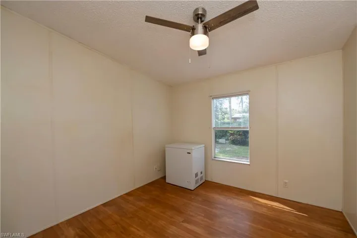 Empty room with ceiling fan, a textured ceiling, and hardwood / wood-style floors