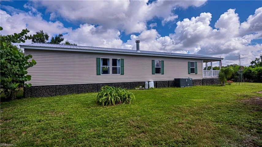 Back of property featuring a yard and central AC