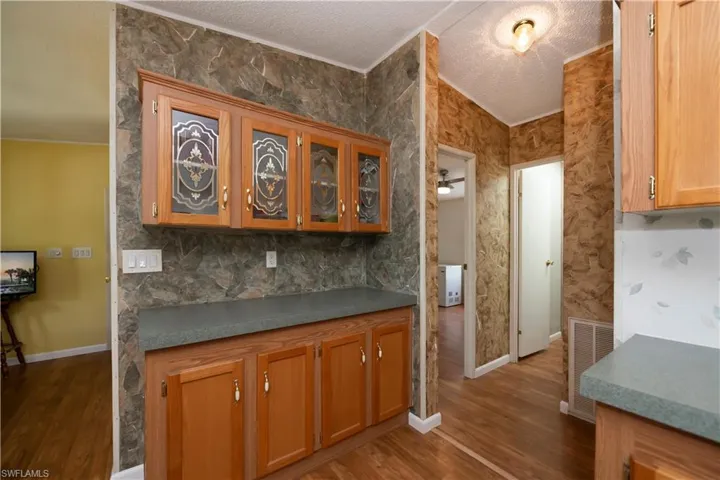 Kitchen featuring a textured ceiling, crown molding, and dark hardwood / wood-style flooring