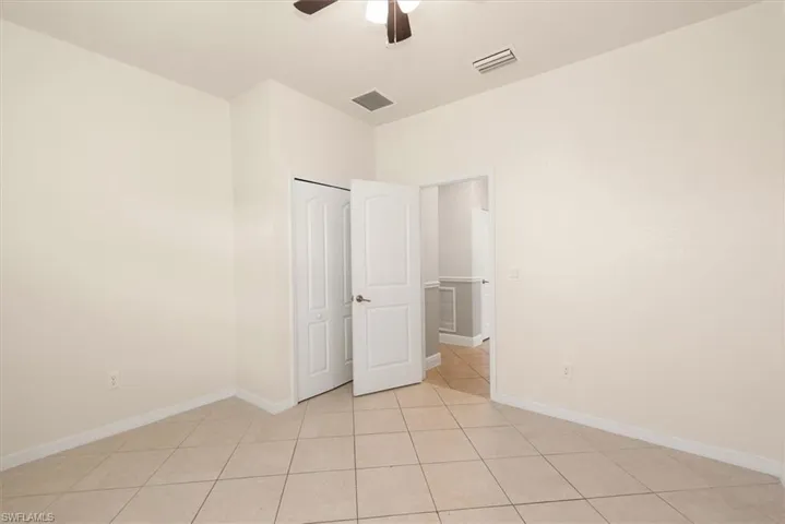 Original view of bedroom 2 with tile flooring, neutral finishes, and ceiling fan.