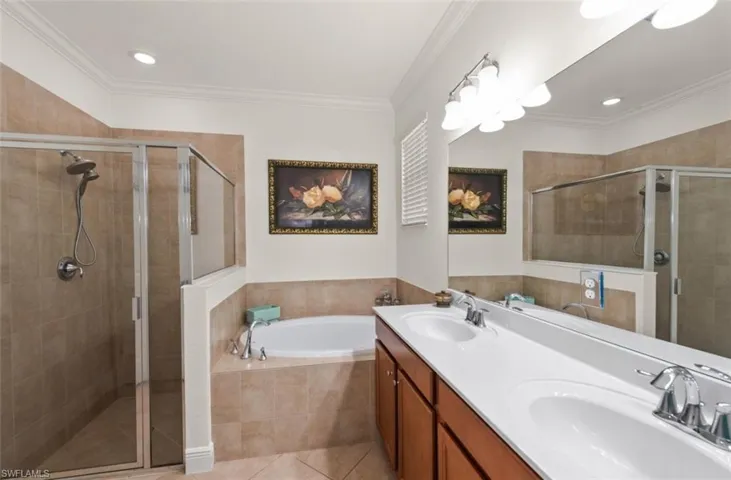 Primary bathroom features a glass enclosed walk in shower, separate soaking tub, and vanity with sink.