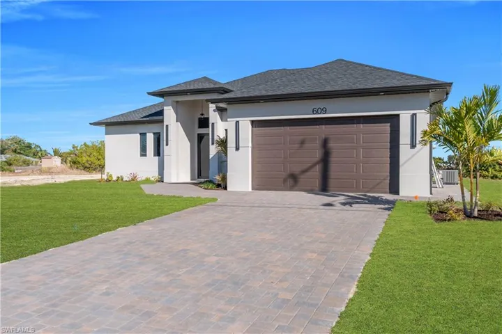 Prairie-style house with a front yard, a shingled roof, stucco siding, driveway, and an attached garage