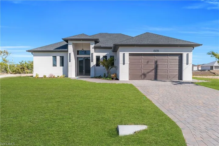 Prairie-style home with stucco siding, a front lawn, decorative driveway, a shingled roof, and an attached garage