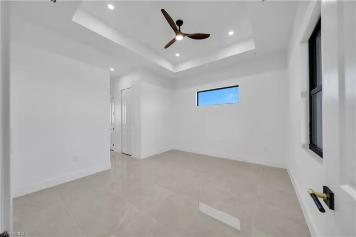 Empty room with ceiling fan, recessed lighting, a tray ceiling, and light tile patterned floors