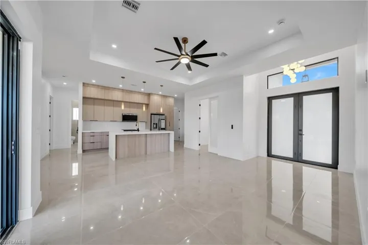 Unfurnished living room featuring french doors, a ceiling fan, recessed lighting, and a raised ceiling