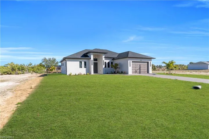 Prairie-style home featuring a front yard, stucco siding, driveway, and an attached garage