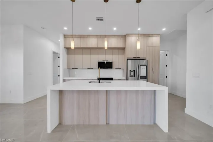 Kitchen with light wood finish cabinets, modern cabinets, and light stone countertops