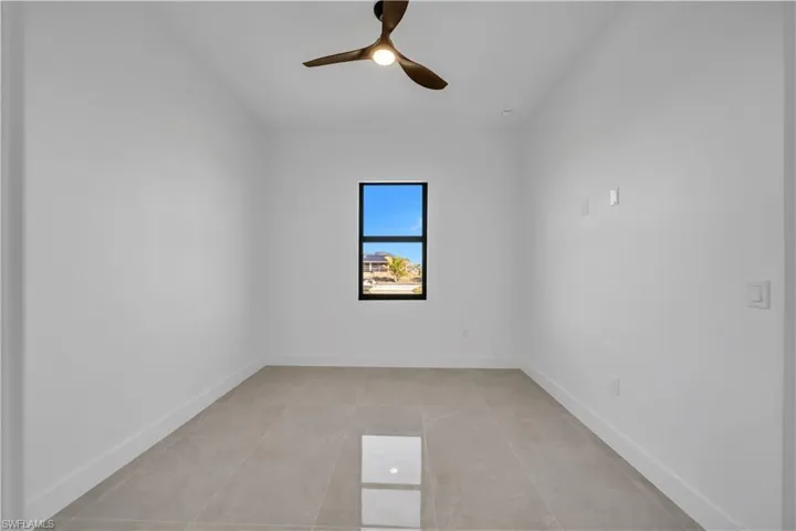 Empty room with ceiling fan and light tile patterned flooring