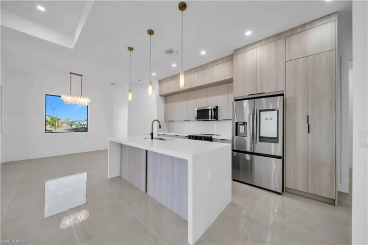 Kitchen with light wood finish cabinetry, stainless steel appliances, light stone counters, and modern cabinets